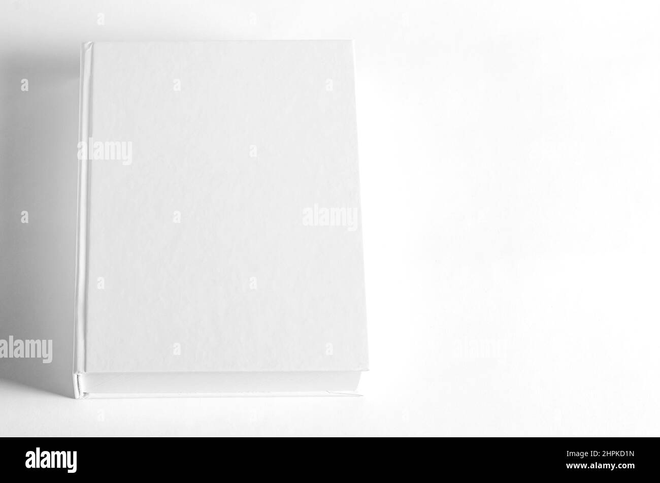 Mockup di libro quadrato chiuso su sfondo di carta testurizzata bianco. Sfondo parete Foto Stock