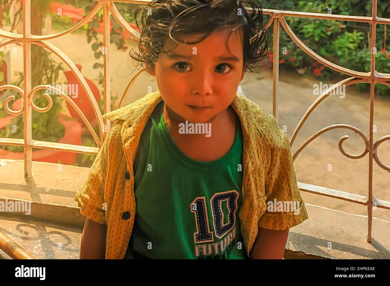 Un ritratto di un bambino / bambino / bambino indiano orientale con una camicia senza bottoni guardando la fotocamera con un look divertito. Foto Stock