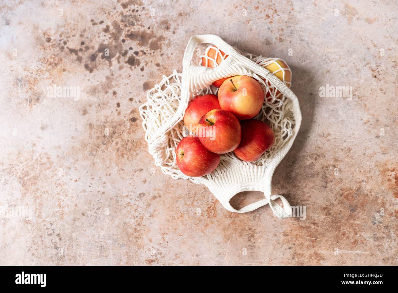 Mele rosse fresche in una borsa a mano su sfondo beige. Vista dall'alto Foto Stock