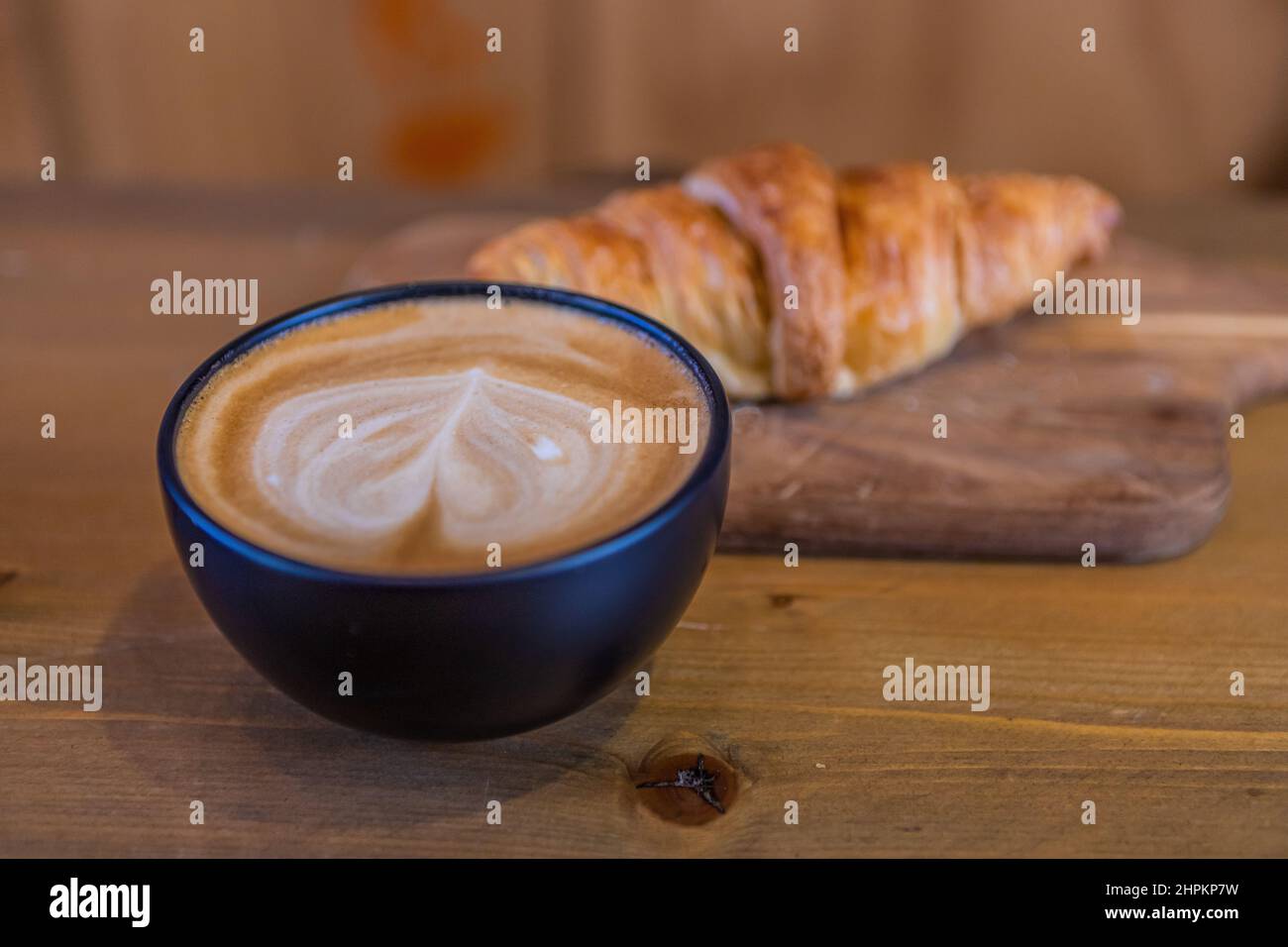 Caffè bianco piatto con croissant su un tavolo di legno Foto Stock