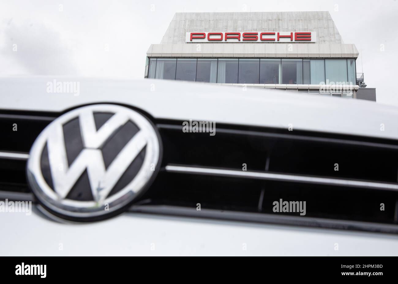 Stoccarda, Germania. 22nd Feb 2022. Il logo Volkswagen è visibile presso la sede centrale di Porsche a Stuttgart-Zuffenhausen di fronte a un edificio con scritta Porsche. Il Gruppo Volkswagen vuole portare al pubblico la sua controllata Porsche AG. Credit: Christoph Schmidt/dpa/Alamy Live News Foto Stock