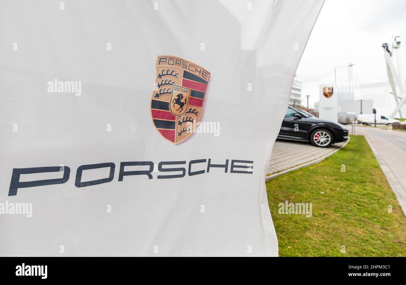 Stoccarda, Germania. 22nd Feb 2022. Una bandiera Porsche vola di fronte ad una vettura Porsche presso la sede centrale della società di Stoccarda-Zuffenhausen. Il Gruppo Volkswagen vuole portare al pubblico la sua controllata Porsche AG. Credit: Christoph Schmidt/dpa/Alamy Live News Foto Stock