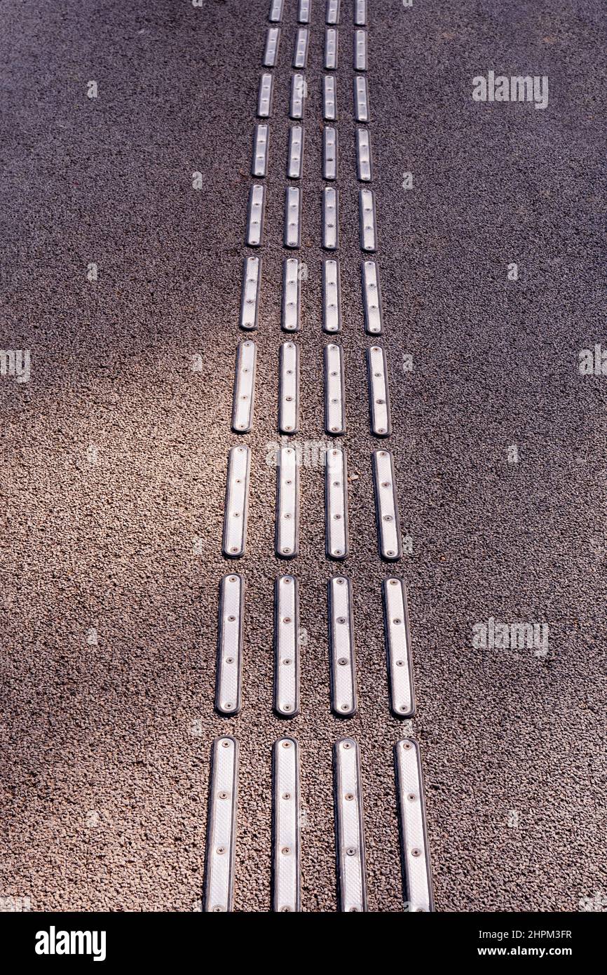 Primo piano di occhi di gatto metallici o marcatore di guida per pavimentazioni per catarifrangenti disabilitati modello di texture su asfalto. Foto di alta qualità Foto Stock