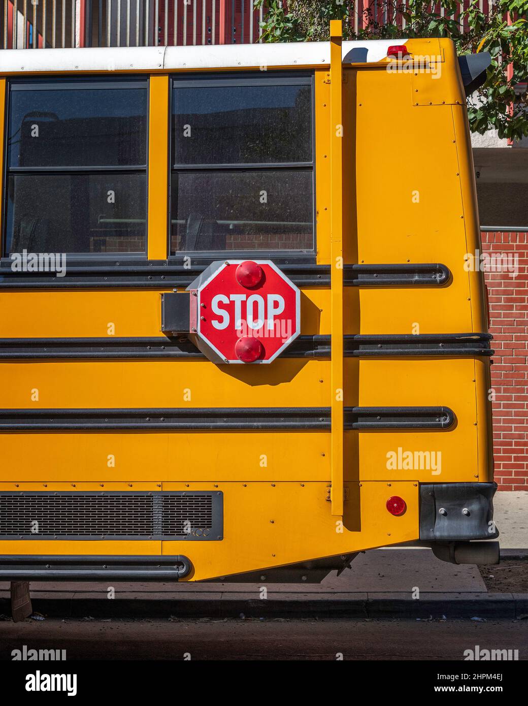 Parte posteriore di un autobus scolastico giallo con segnale di stop attaccato Foto Stock