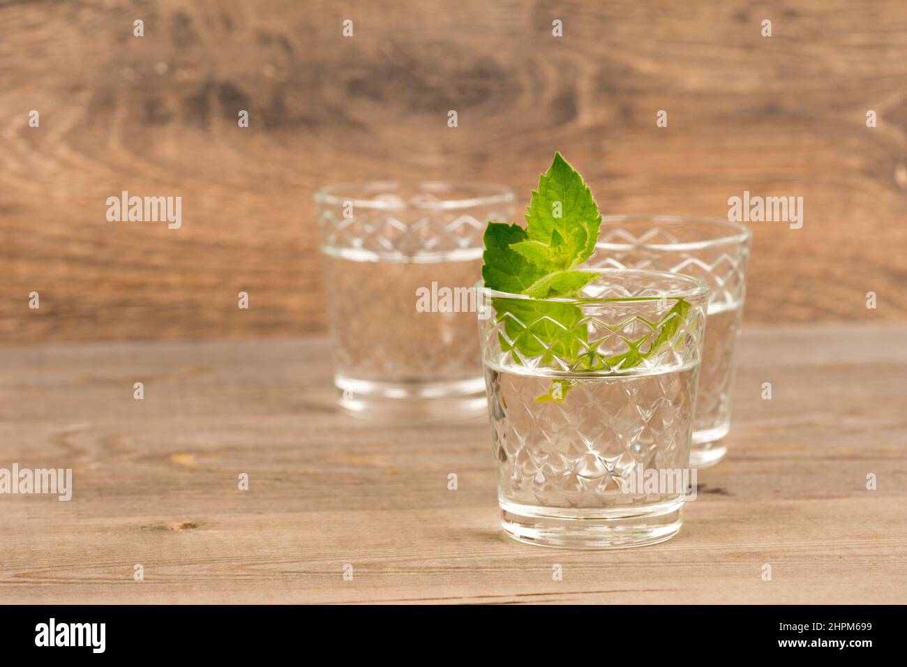 vodka con menta in bicchieri a scatto su tavola rustica in legno Foto Stock
