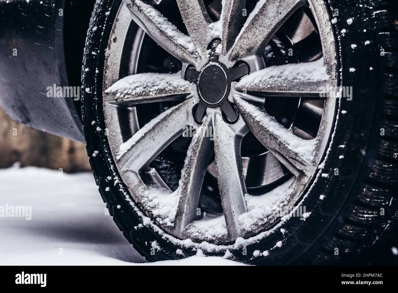 Foto del cerchione e del pneumatico auto sporchi in piedi su strada innevata. Foto Stock