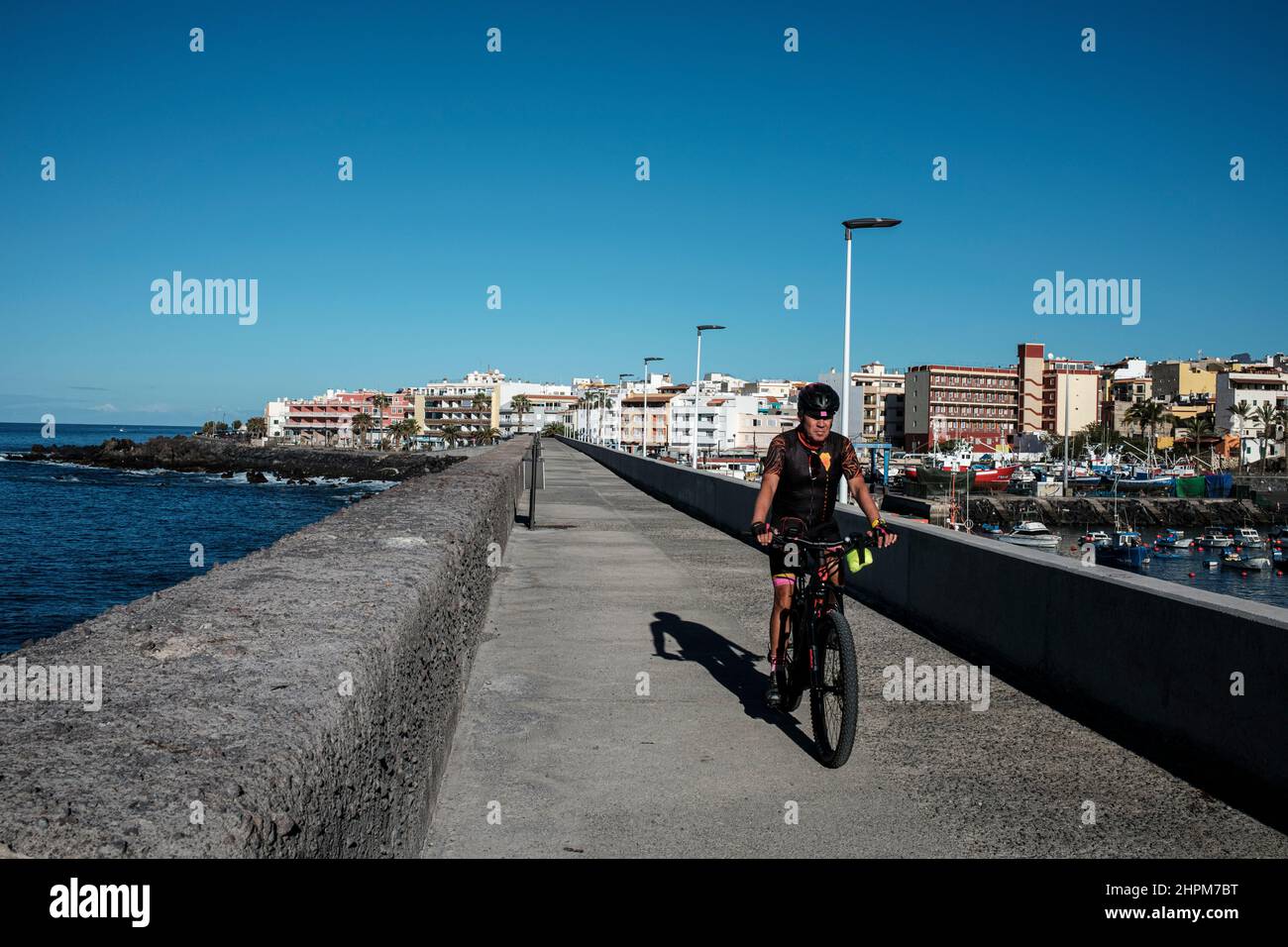 Ciclista sulla parete del porto a Playa de San Juan, Tenerife, Isole Canarie, Spagna Foto Stock