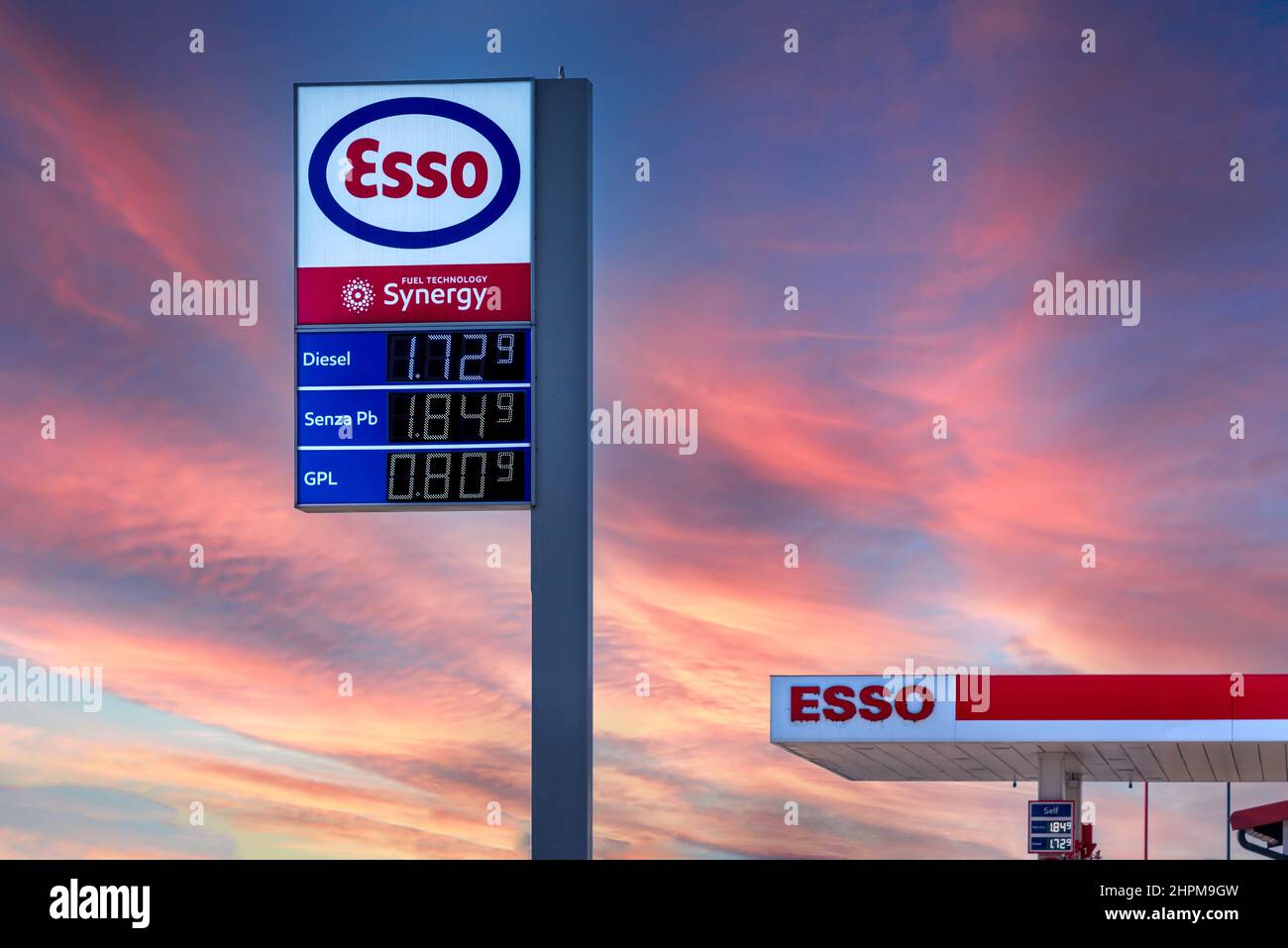 Fossano, Italia - 22 febbraio 2022: Logo esso con carburante visualizzazione del prezzo euro sul cielo al tramonto colorato, esso è un marchio dell'industria petrolifera globale gi Foto Stock