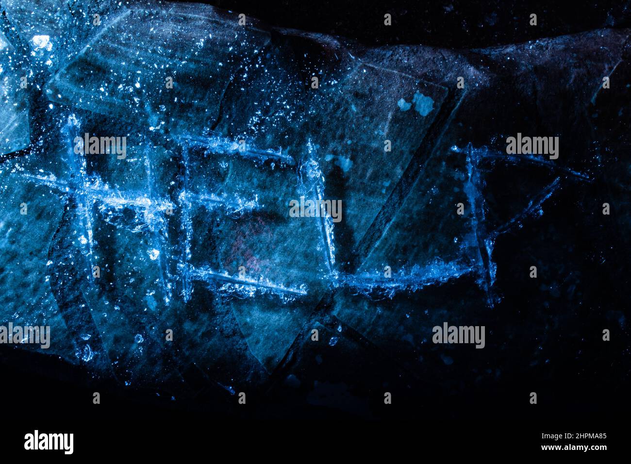 Foto della parola di aiuto graffiata sulla superficie di ghiaccio incrinata su sfondo scuro. Foto Stock