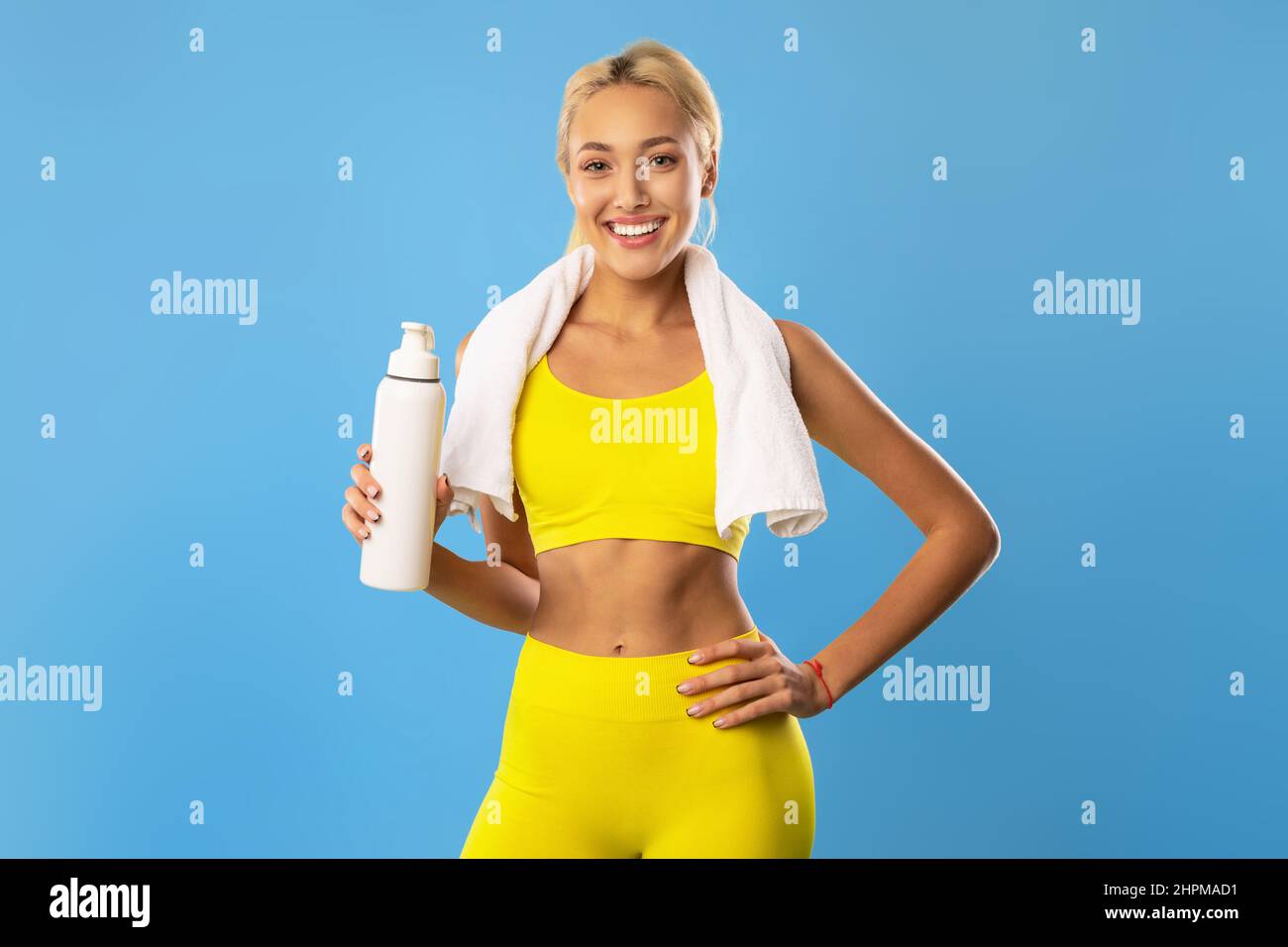 Donna sorridente sportiva in posa in studio con bottiglia d'acqua Foto Stock