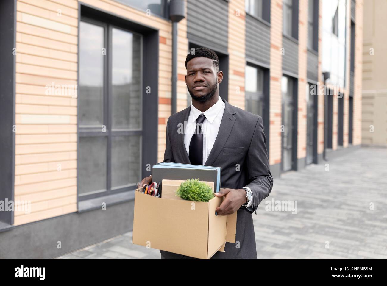 Licenziato africano americano maschio ufficio lavoratore con scatola di personale roba perso lavoro e lasciato senza soldi, andando a casa Foto Stock