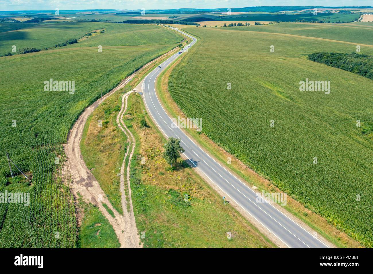Vista dall'alto di un'autostrada tra campi agricoli coltivati. Paesaggio rurale in estate Foto Stock