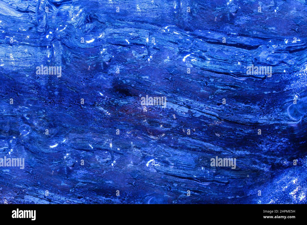Foto di tronco di legno congelato di colore blu ricoperto di tessuto ghiacciato. Foto Stock