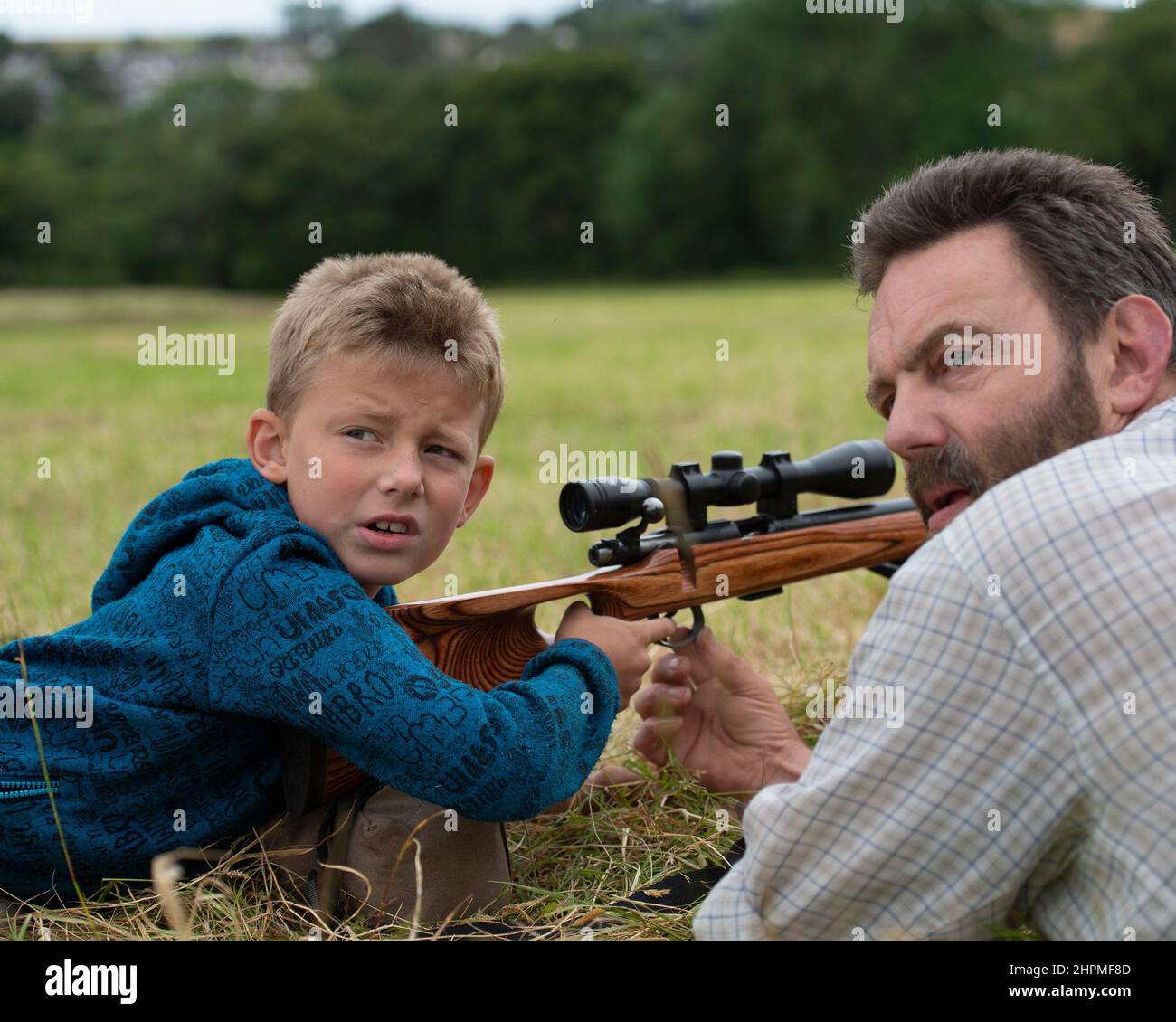 padre che insegna a figlio come usare la pistola a fucile Foto Stock