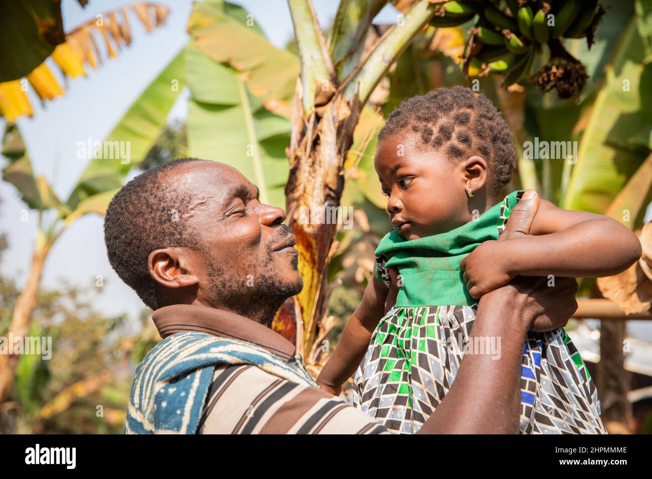 Il padre africano alza la figlia del bambino, momento di amore tra padre e figlia. Foto Stock