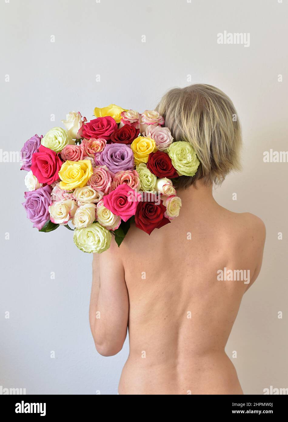 donna nuda che tiene un bouquet colorato di rose Foto Stock