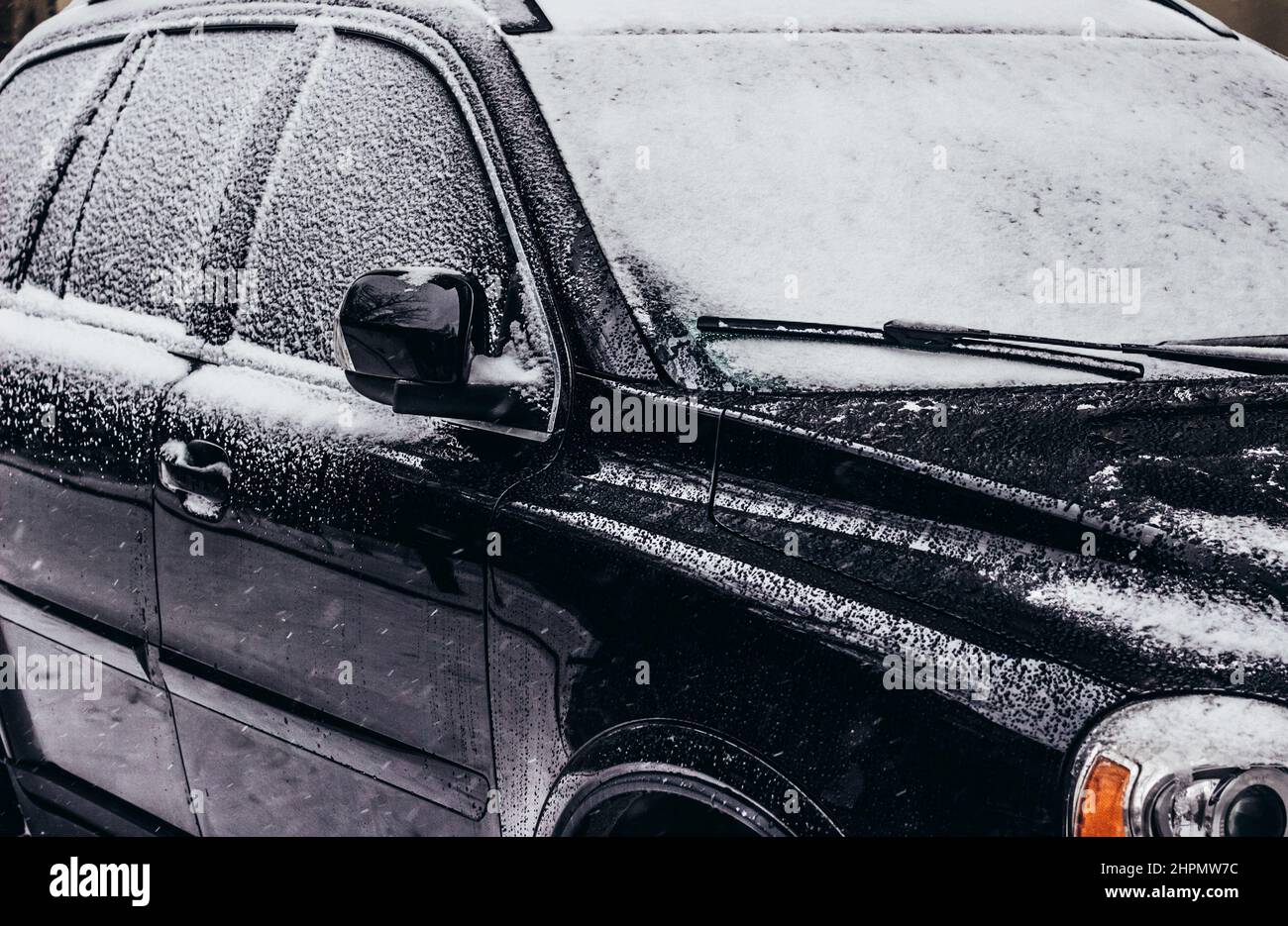 Foto di un veicolo auto di colore nero parcheggiato e coperto di neve. Foto Stock