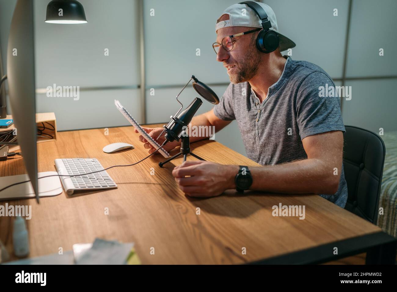 Uomo medio-vecchio Blogger in cuffie leggere testo registrazione voce o fare online webinar o annuncio di notizie. Recor audio moderno da studio Foto Stock