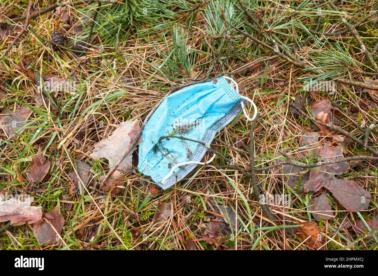 Scartato maschera medica monouso nella foresta, fuoco selettivo. Foto Stock