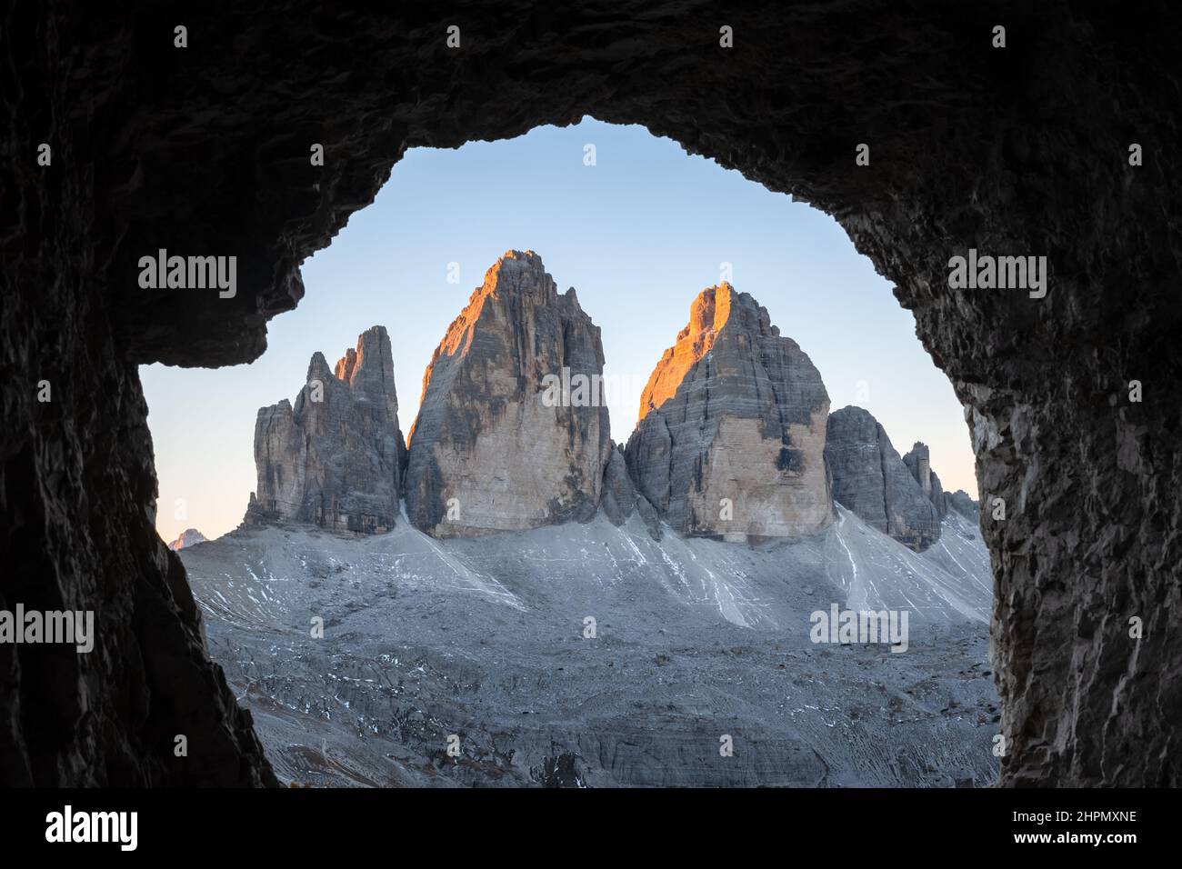 Tre Cime di Lavaredo cime in un'incredibile luce arancione al tramonto. Vista dalla grotta in montagna sulle tre cime di Lavaredo, Alpi dolomitiche, Italia, Europa. Fotografia di paesaggio Foto Stock