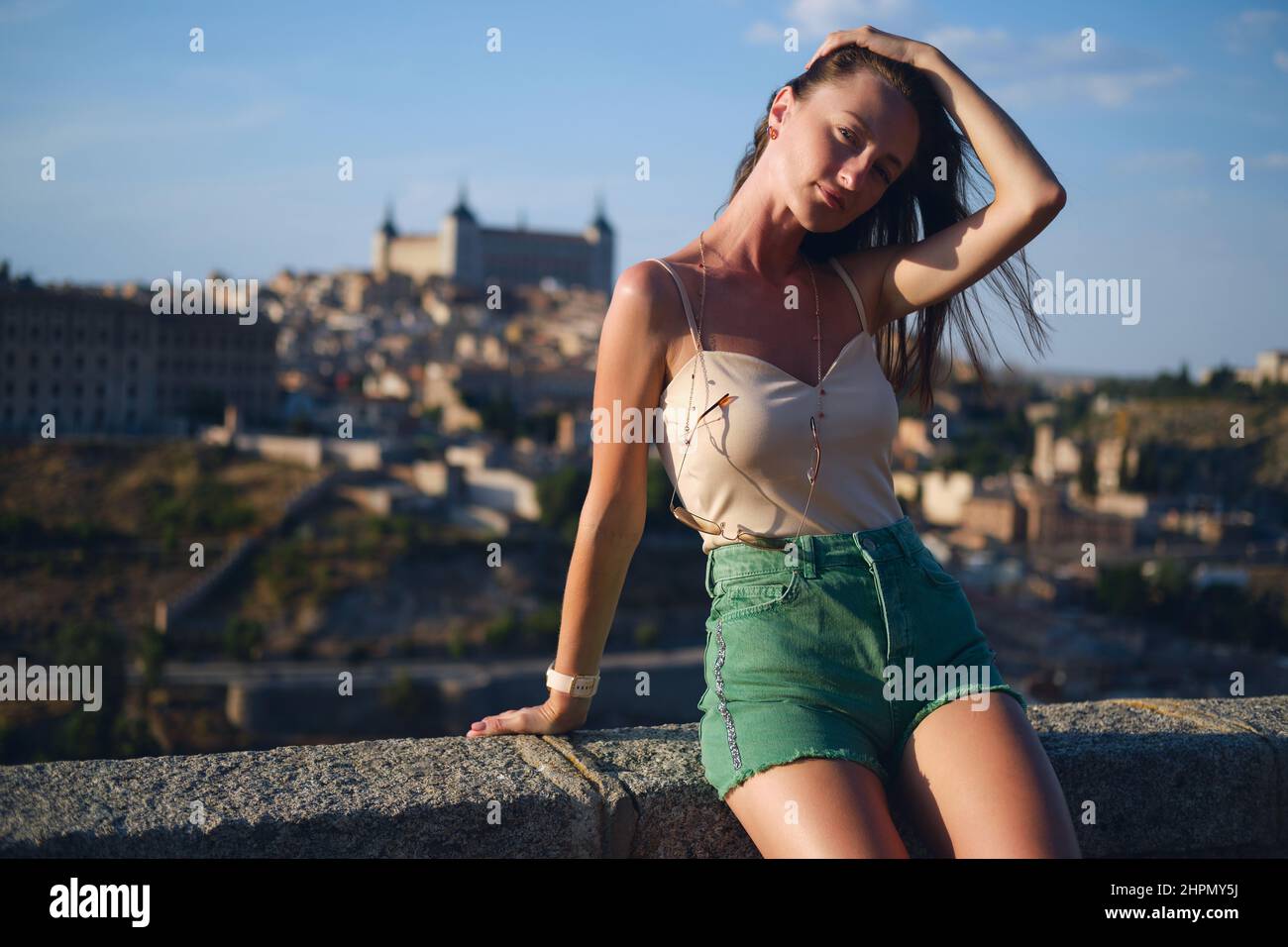 Bella giovane 30s donna che si posa contro Toledo paesaggio urbano sfondo. Le donne turistiche godono di luoghi famosi e luoghi di interesse. Castilla-la Mancha. Viaggi des Foto Stock