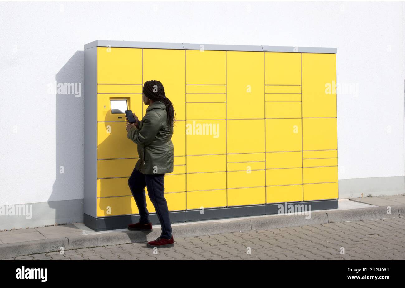 Stazione di imballaggio post automatizzato con la donna sullo schermo di controllo che tiene il telefono cellulare Foto Stock