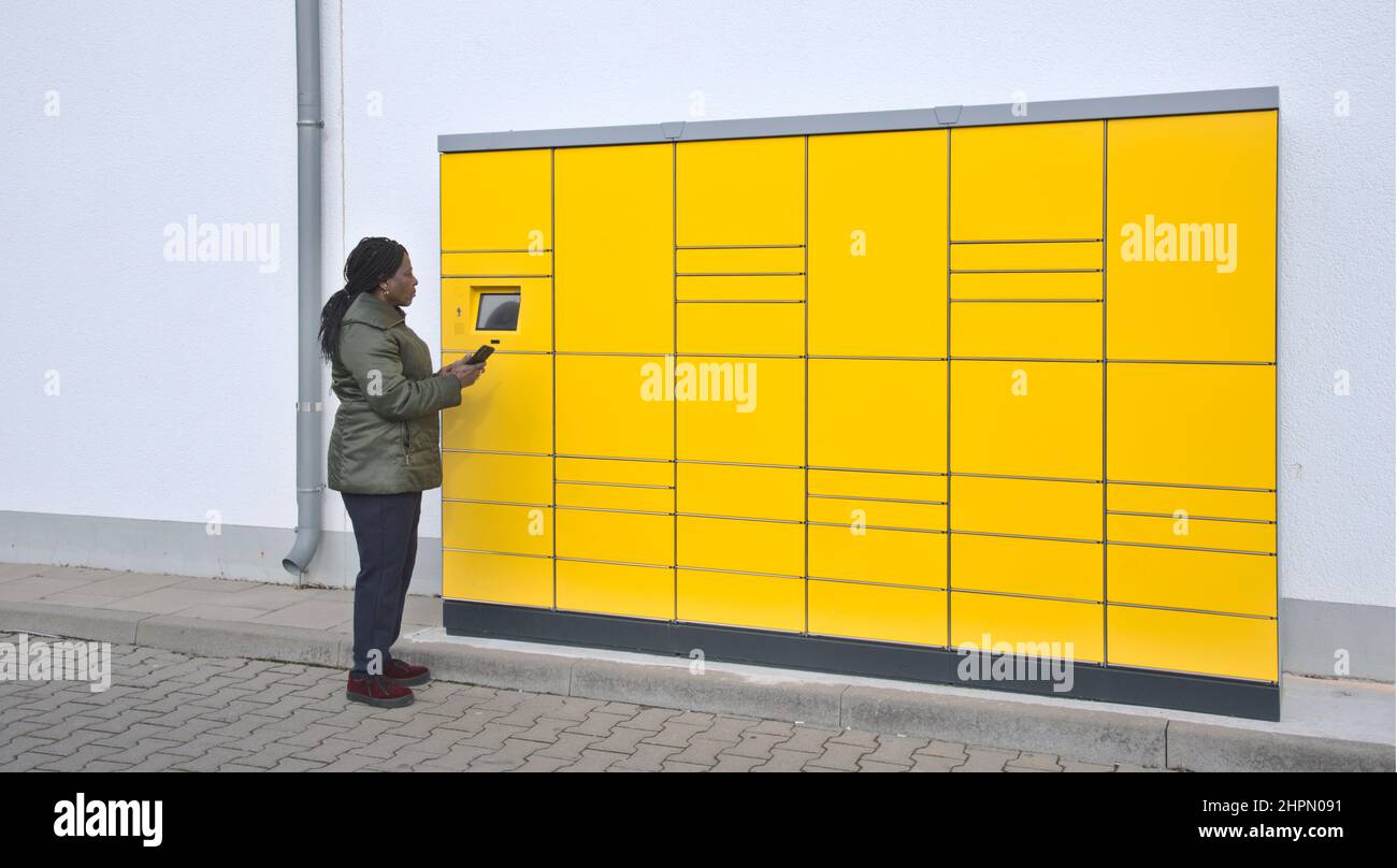 Stazione di imballaggio post automatizzato con la donna sullo schermo di controllo che tiene il telefono cellulare Foto Stock