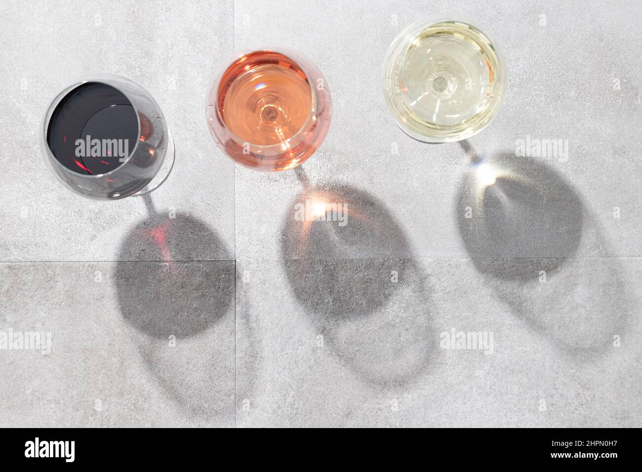 Vino rosso, bianco e rosato in calici isolati su fondo di cemento con spazio copia. Vista dall'alto. Foto Stock