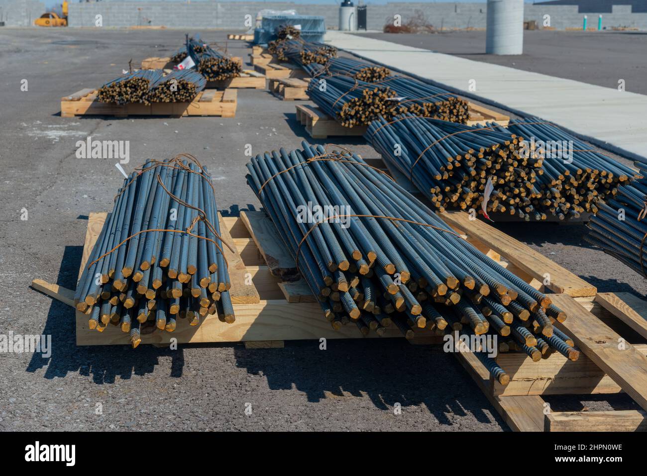 Sparo orizzontale di pile di barrette in acciaio su pallet in legno in un nuovo cantiere industriale. Foto Stock