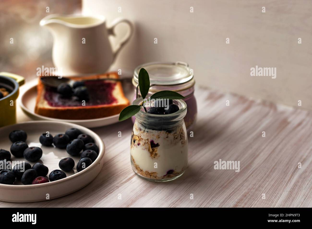 Avena laminata muesli granola parfait, fiocchi d'avena per una notte in vaso di vetro, pane tostato, marmellata di mirtilli Foto Stock