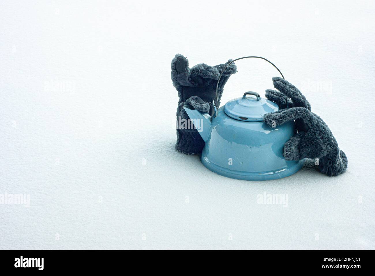 Scaldi. La neve circonda i guanti di inverno e il teakettle del furry. Confrontare caldo a freddo, mantenere caldo all'interno e all'esterno. Guanti sulla neve. Spazio di testo. Foto Stock