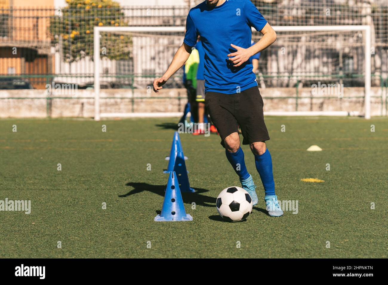 giocatore di calcio irriconoscibile che dribbling i coni di calcio su campo artificiale di erba sintetica Foto Stock