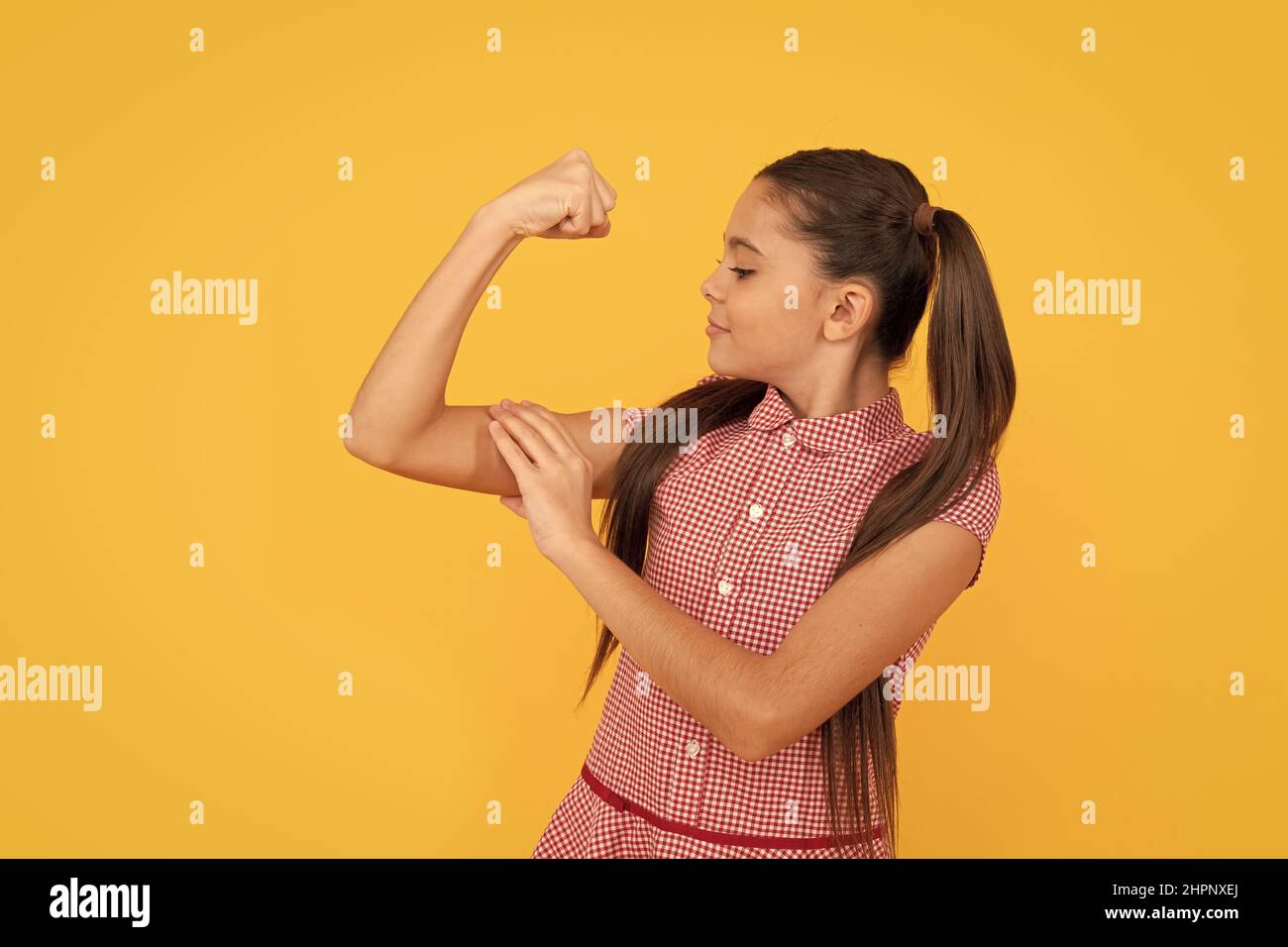 Potenza della ragazza. Femmina bambino braccio flessibile sfondo giallo. Gesto di potenza e forza. ALIM. CRL Foto Stock