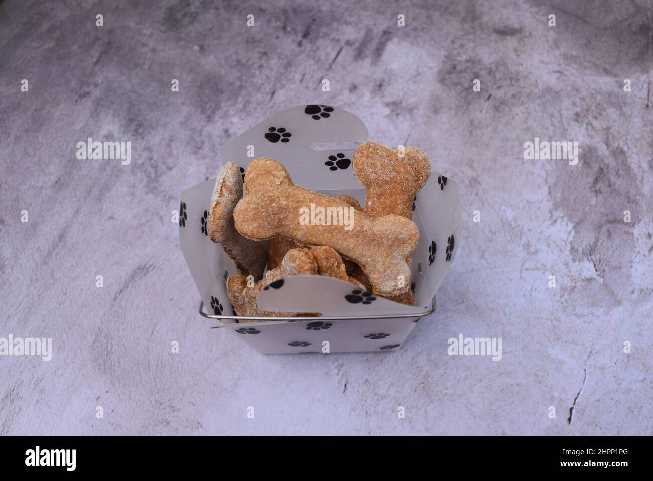 Dolci fatti in casa per cani "a forma di osso" nel contenitore 'zampe'. Foto Stock