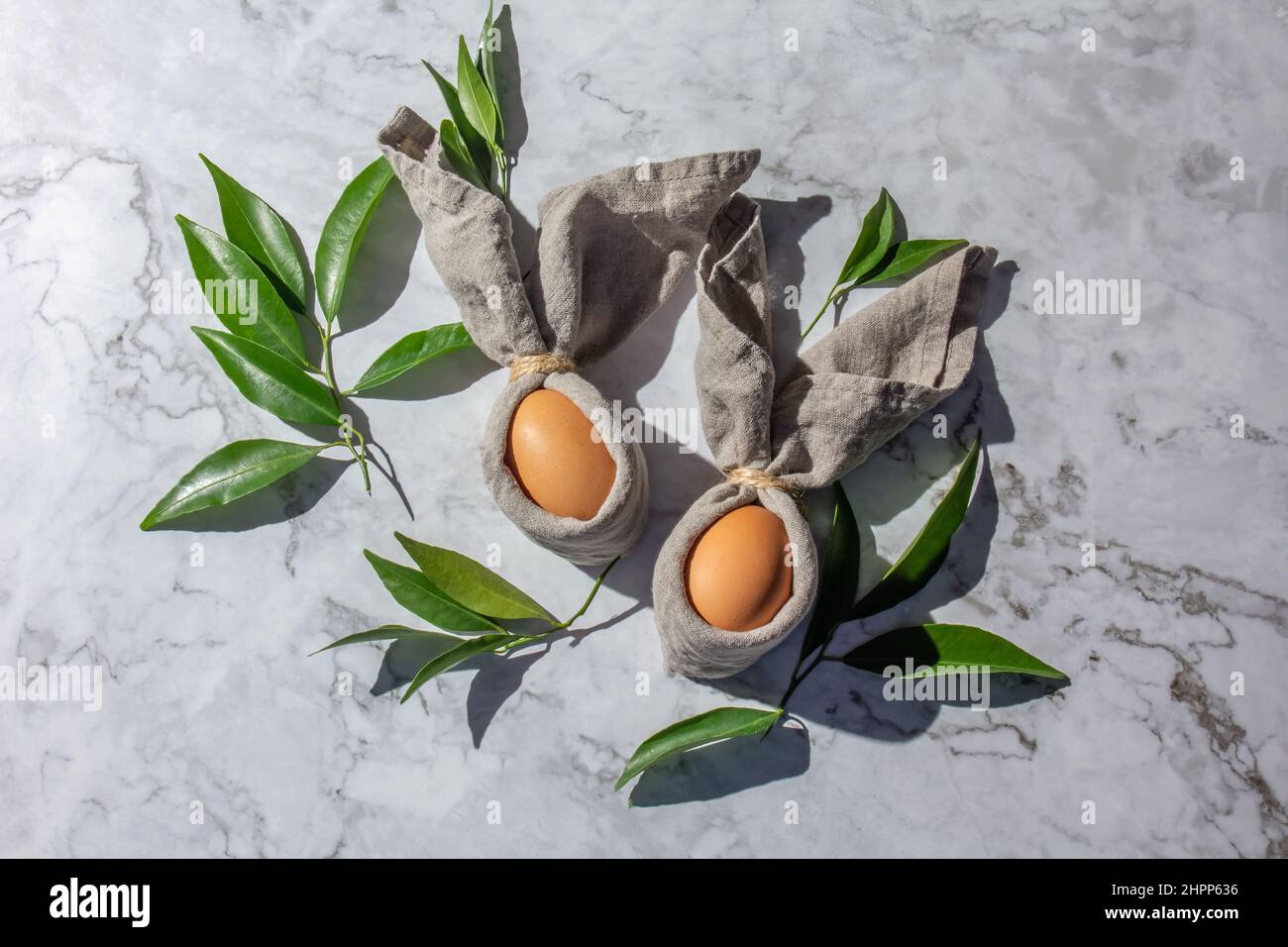 Sfondo di pasqua festivo con uova conigliate di Pasqua su tovagliolo di lino. Decorazione pasquale, vista dall'alto. Spazio di copia. Foto Stock