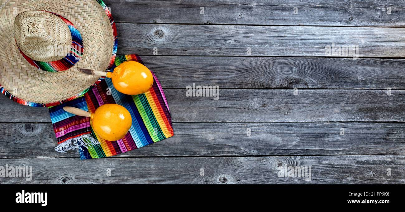 Messico Cinco de Mayo sfondo con grande sombrero, serape e maracas in piano vista su legno vintage Foto Stock