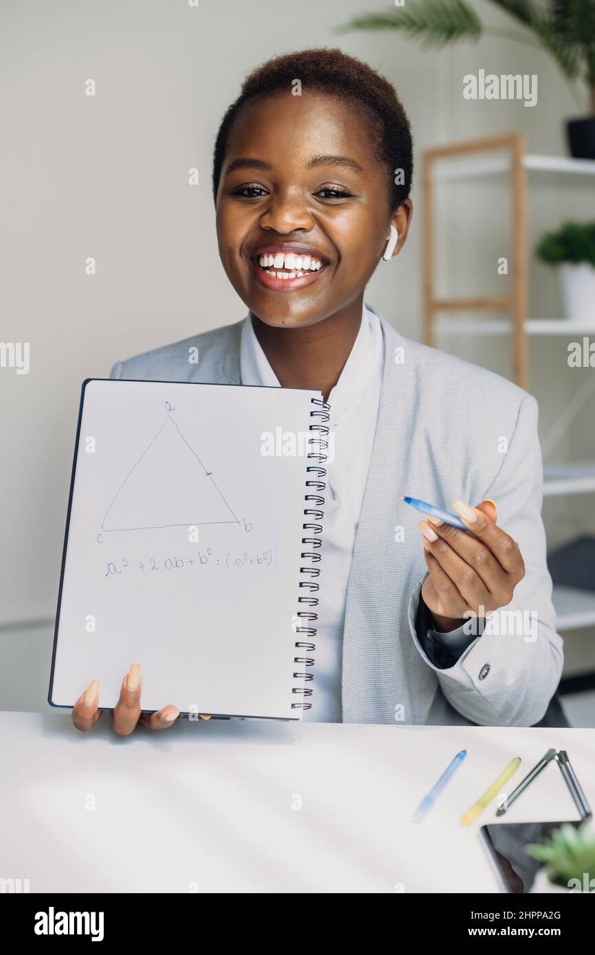 Vista frontale di una donna afroamericana che tiene un notebook che parla con i colleghi che si trovano in ufficio. Lavoratore di ufficio. Video online. Colloquio di lavoro. Foto Stock