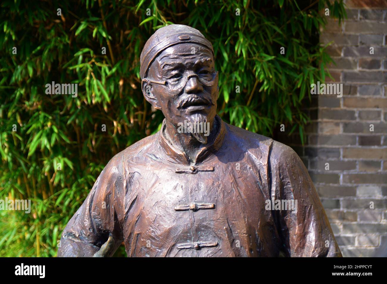 Primo piano di una statua di uno studioso cinese in giardino in una giornata di sole Foto Stock