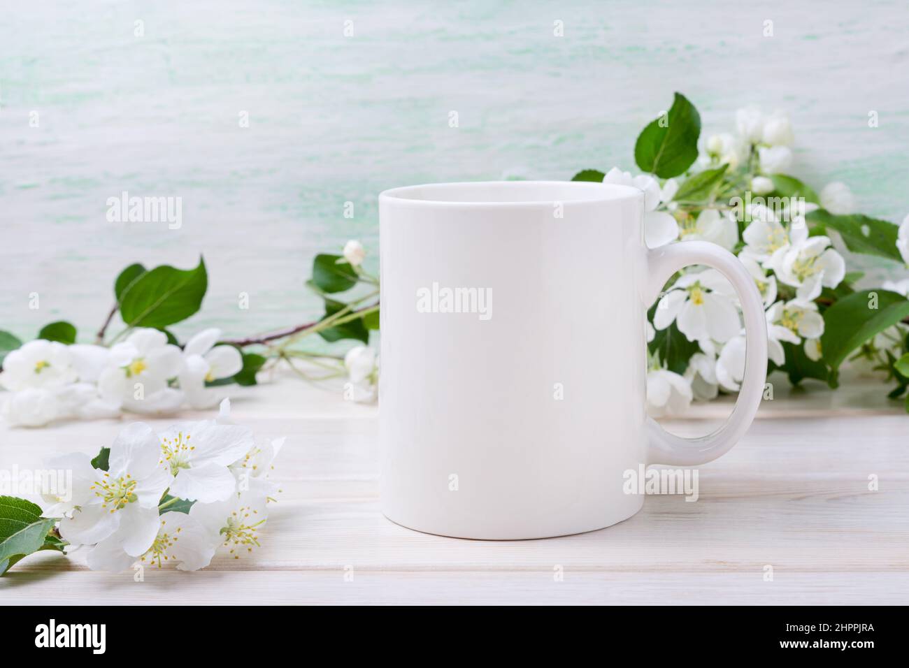 Caffè bianco mockup tazza con teneri fiori di mela fiore. Tazza vuota per la promozione del design, modello in stile Foto Stock