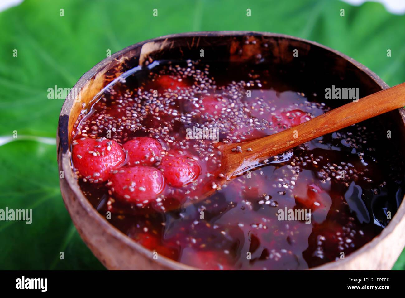 Vista dall'alto fragole rosse zuccherate in ciotola che fanno da conchiglie di cocco su foglia verde, frutta rossa fresca da Lat per giorno d'estate, cibo yummy Foto Stock