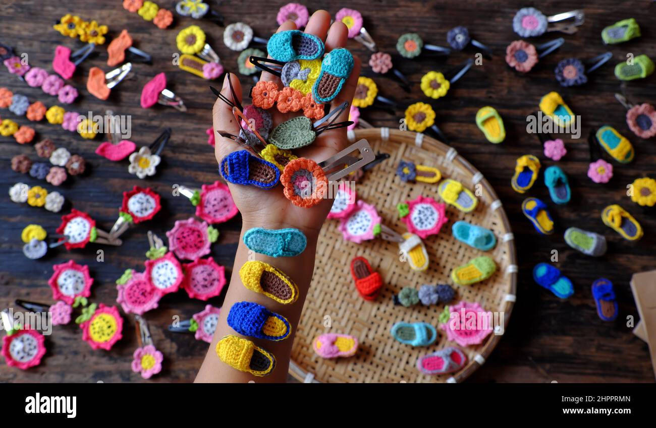 Vista dall'alto vietnamita donna mano tenere prodotto fatto a mano, uncinetto capelli spilla in molte forme e colorato, grazioso artigianato accessori regalo per la bellezza su bla Foto Stock
