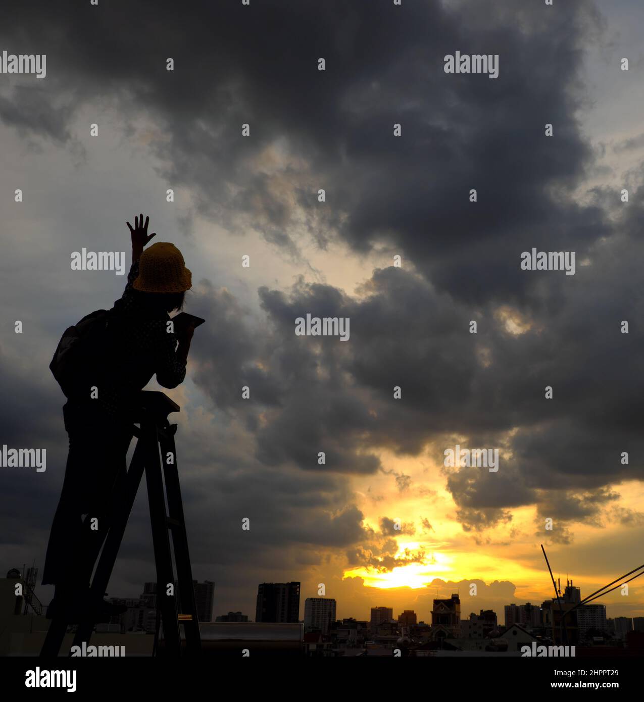 Scena stupefacente da donna vietnamita quando rimanere a casa da sociale distanziamento, si fa il divertimento al tramonto sul tetto da stand sulla scala quando il sole scende a m Foto Stock