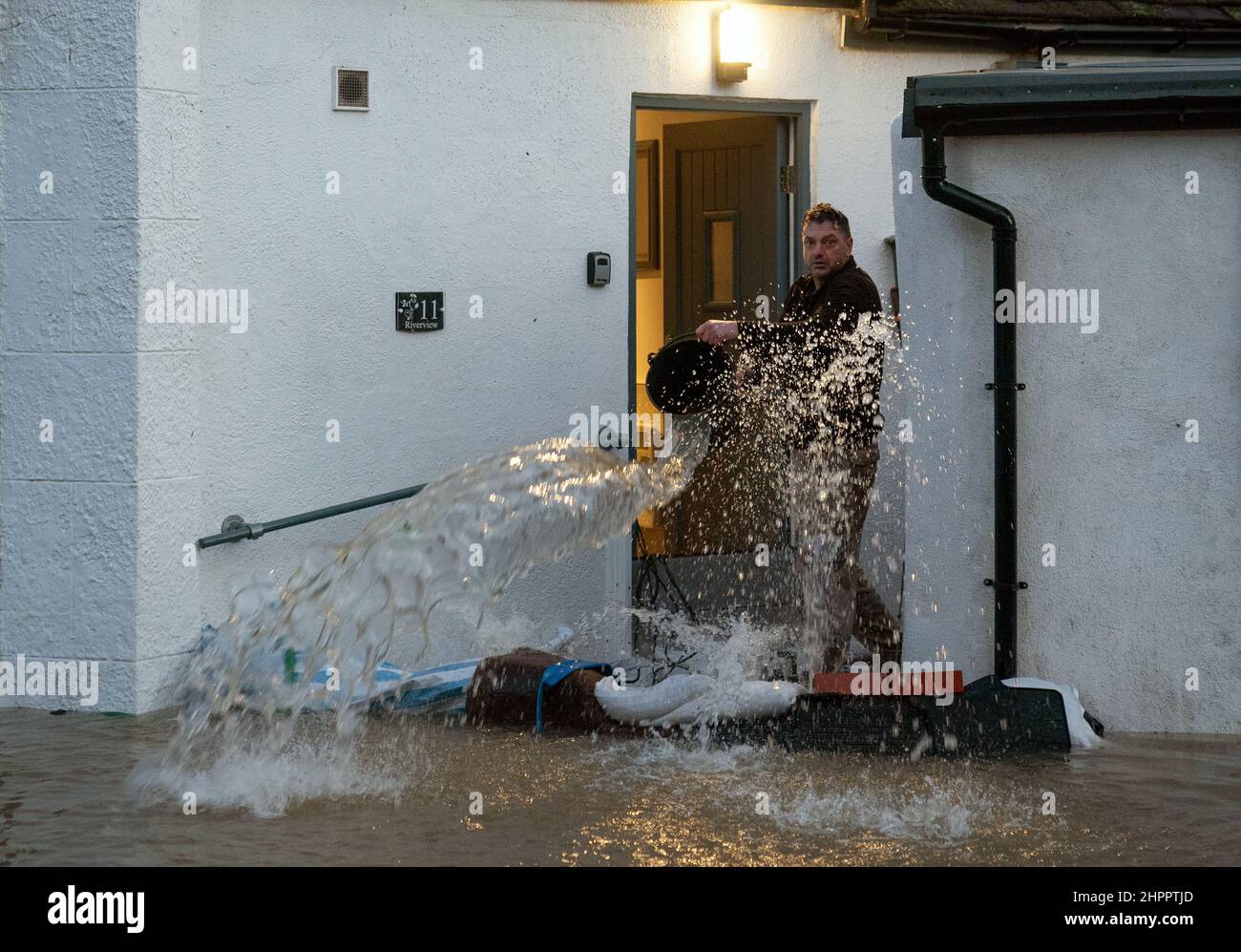 Un uomo getta un secchio d'acqua dalla porta di una casa a Bewdley, nel  Worcestershire, dove l'acqua del fiume Severn ha violato le difese delle  alluvioni della città a seguito di forti