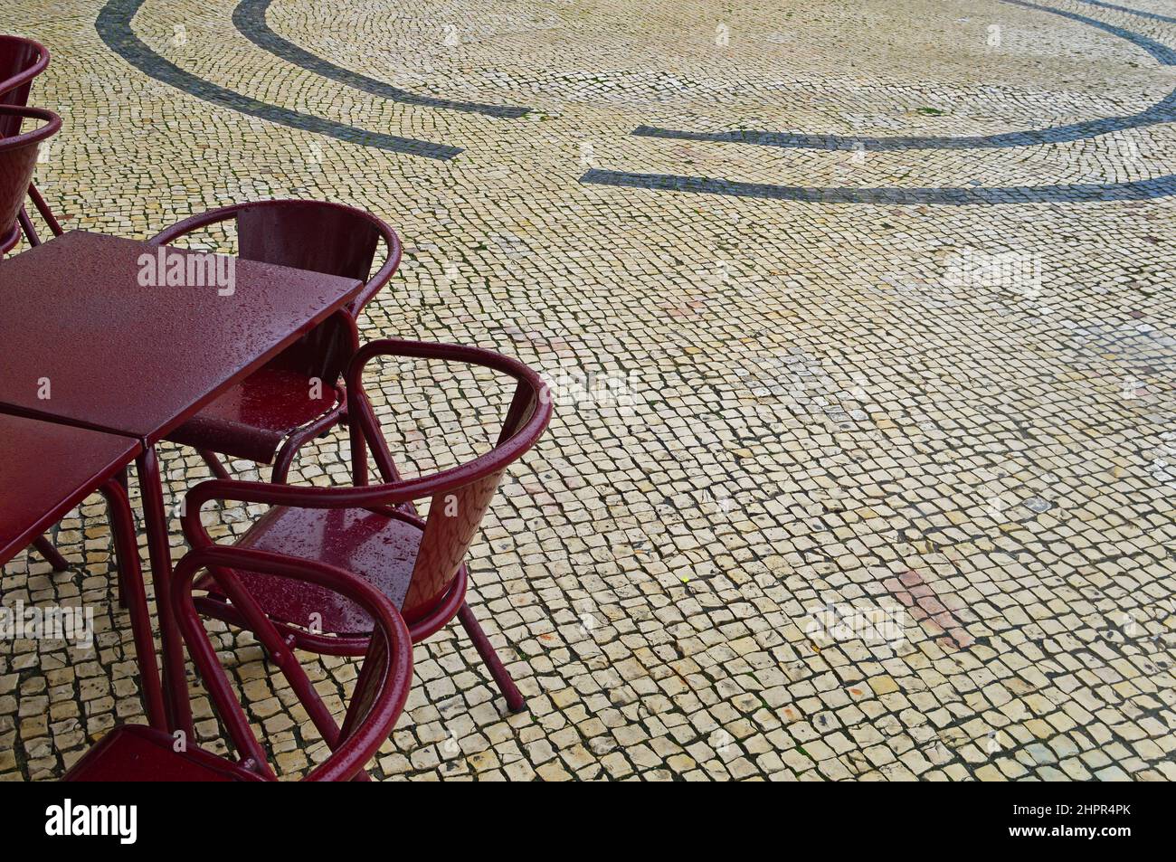 Tavoli e sedie di un caffè di strada in una giornata piovosa a Lisbona, Portogallo. Messa a fuoco selettiva Foto Stock