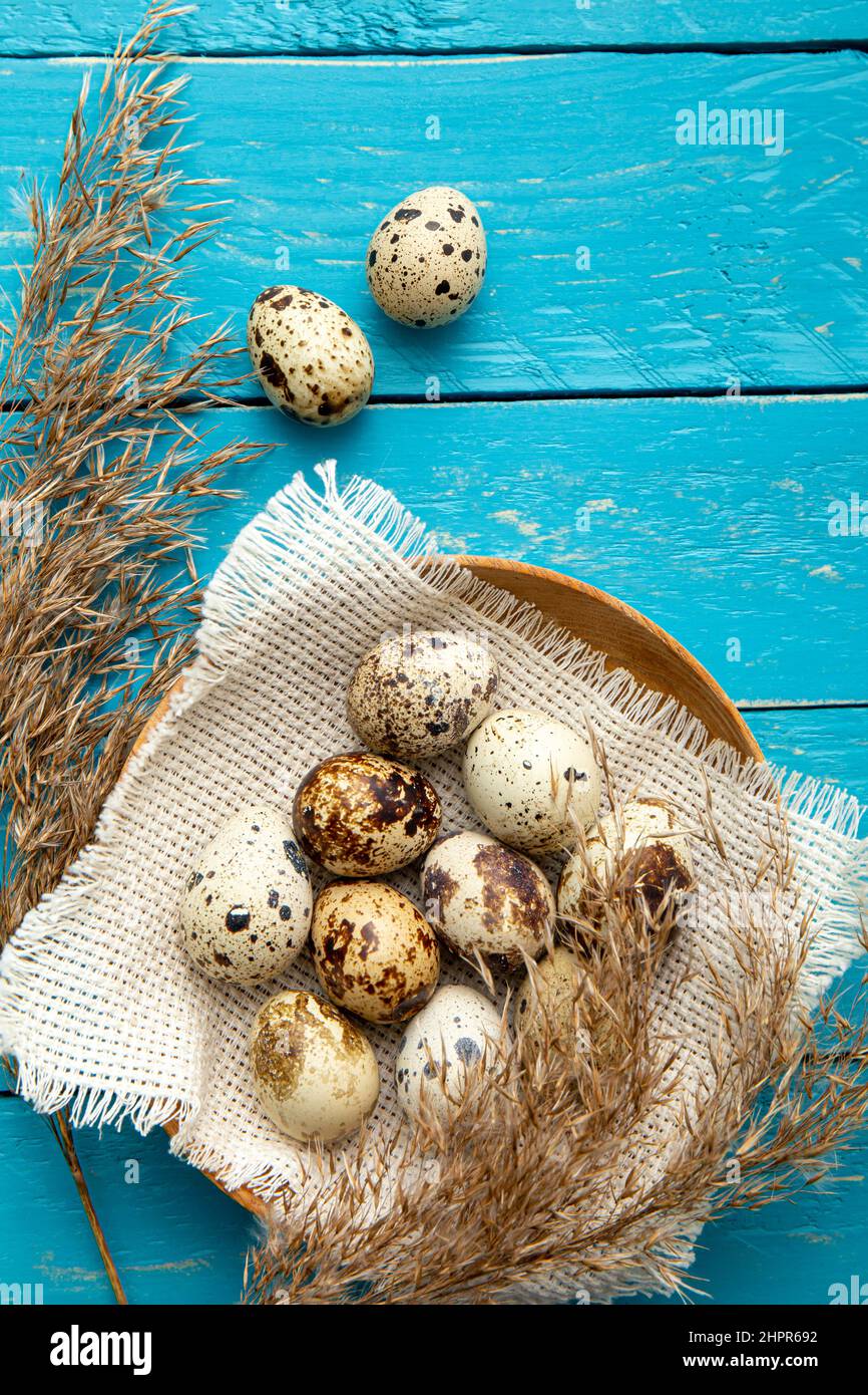Mucchio di uova di quaglia in legno naturale ciotola in interni su sfondo blu tavola di legno. Vista con disposizione piatta, molto spazio per la copia. Concetto di cibo sano. Foto Stock