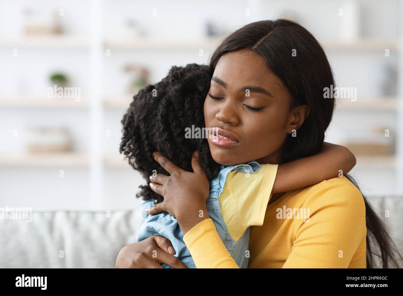 La donna afroamericana che si prende cura di abbracciando la bambina, confortando il suo bambino sconvolto Foto Stock