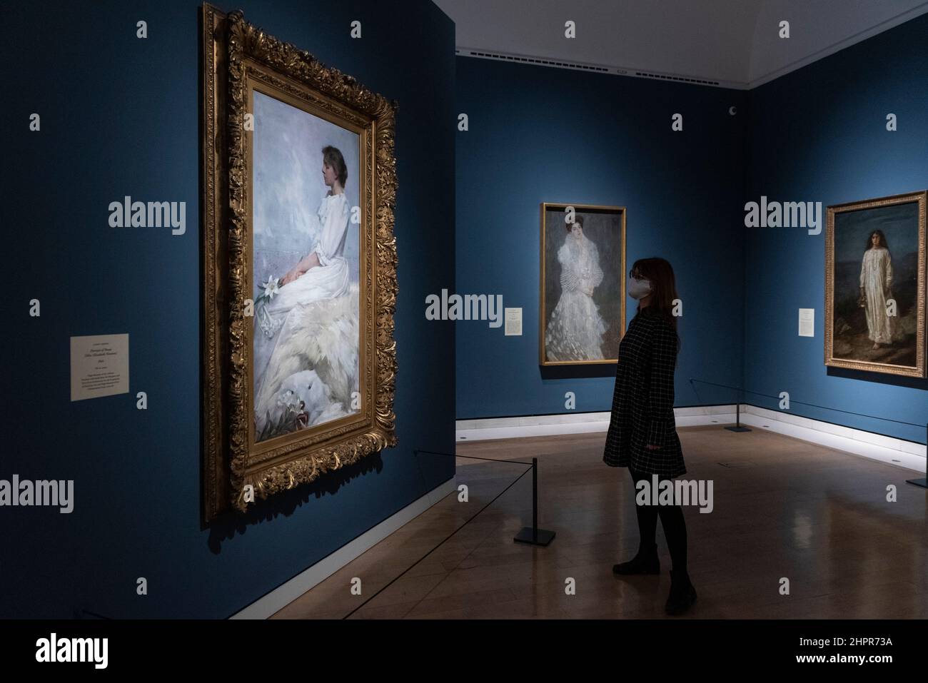 Londra, Regno Unito. 23 febbraio 2022. Una donna vede (L) 'Ritratto di Bessie (Miss Elizabeth Newton)', 1892, di Albert Herter. Anteprima di “Whistler’s Woman in White: Joanna Hiffernan”, la prima mostra a esaminare l’importante ruolo svolto dal modello irlandese Joanna Hiffernan di James McNeill Whistler. Oltre 70 opere sono alla Royal Academy of Arts dal 26 febbraio al 22 maggio 2022. Credit: Stephen Chung / Alamy Live News Foto Stock