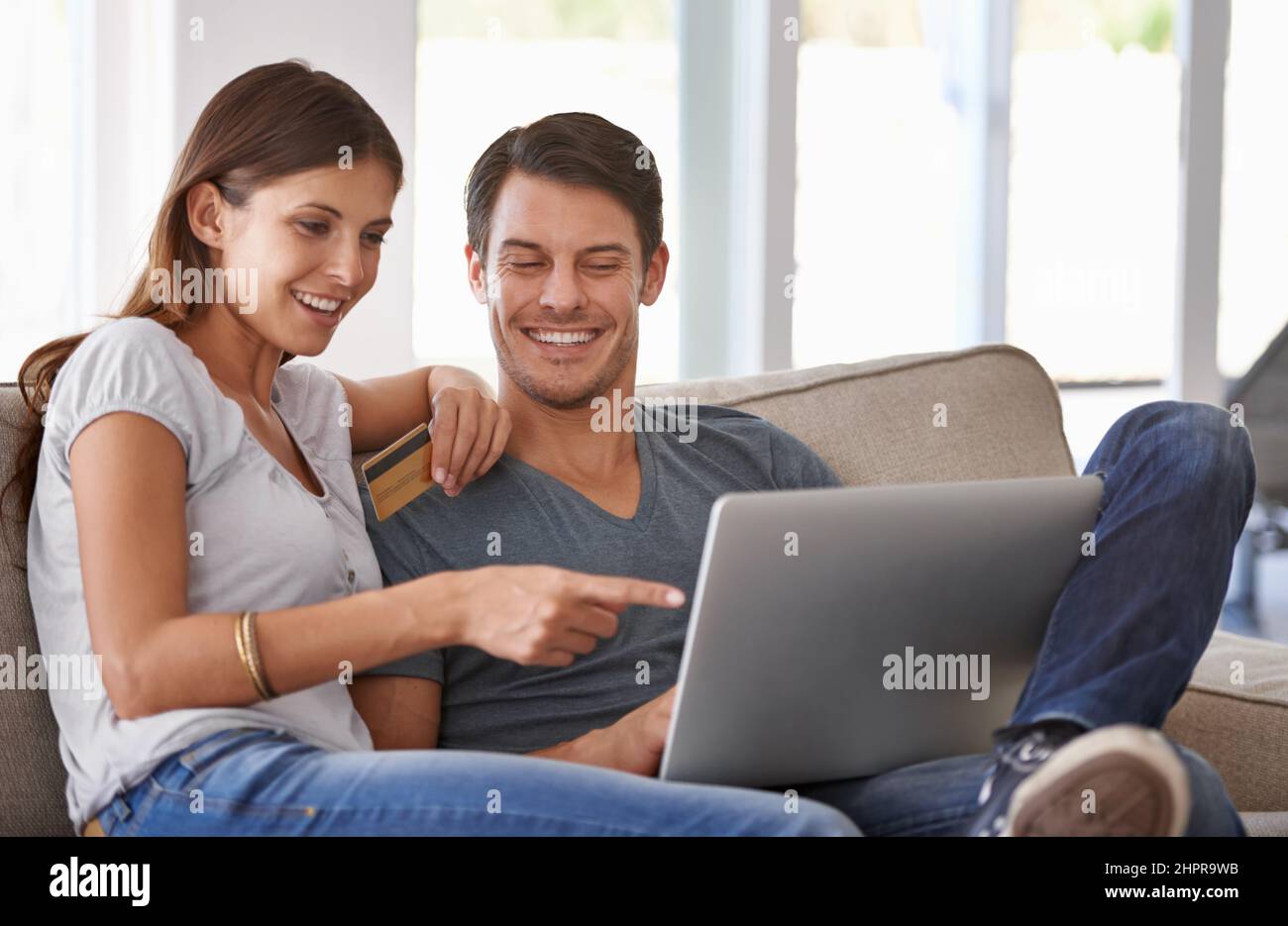 Dovremmo ottenere tutto questo. Una giovane coppia affettuosa che fa un po' di shopping online a casa. Foto Stock