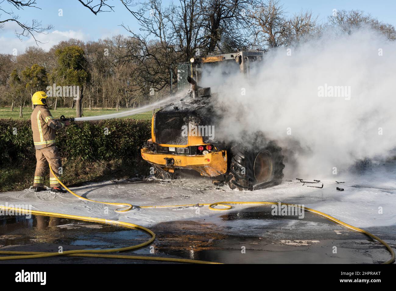 Un vigile del fuoco del servizio antincendio e di soccorso di Hereford & Worcester che utilizza schiuma per estinguere un digger JCB in fiamme a Moccas, Herefordshire, Regno Unito Foto Stock