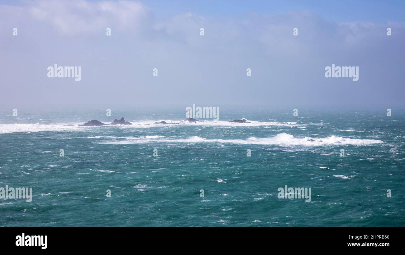 Longships Lighthouse e barriera corallina come visto da Lands End durante una scogliera nord-occidentale Foto Stock
